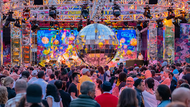 People dance under a giant disco ball on the dance floor at an event for Lincoln Center's Summer for the City