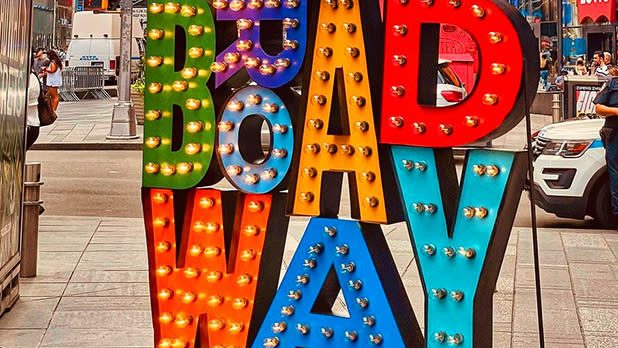 A Broadway sign in different colors lit up in Times Square