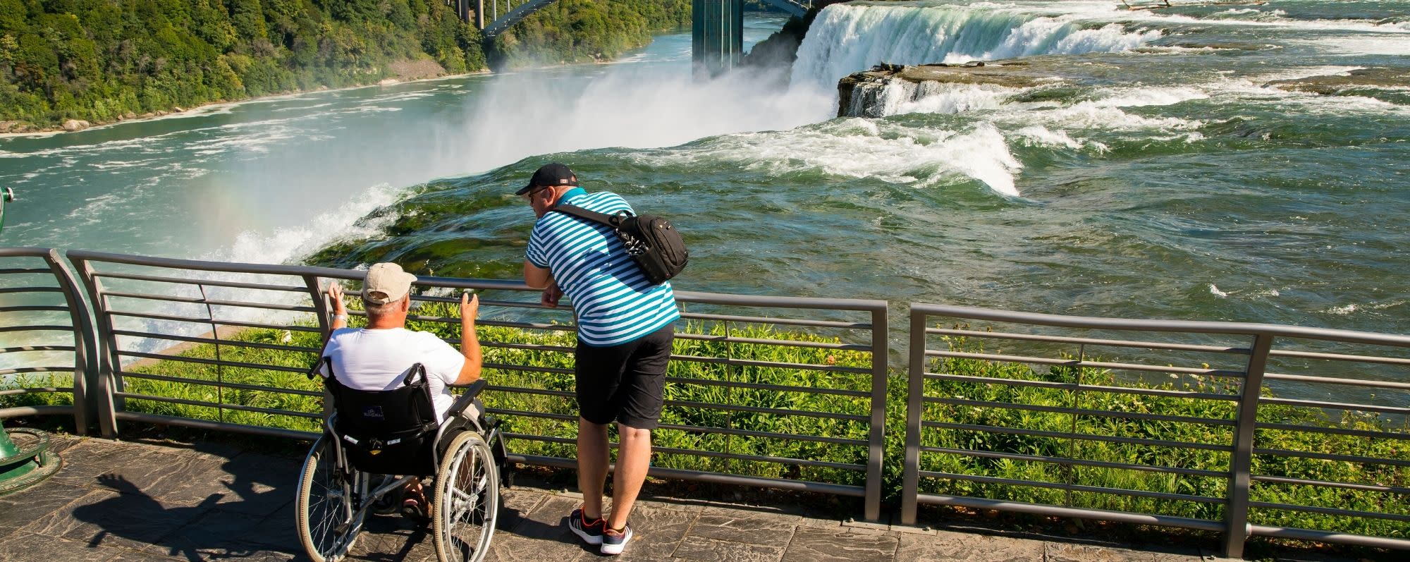 A man in a wheelchair and a companion look out at Niagara Falls