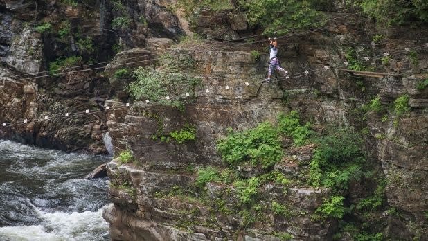 A girl walks on a suspended walkway over the Ausable Chasm on the Ausable Chasm Adventure Trail