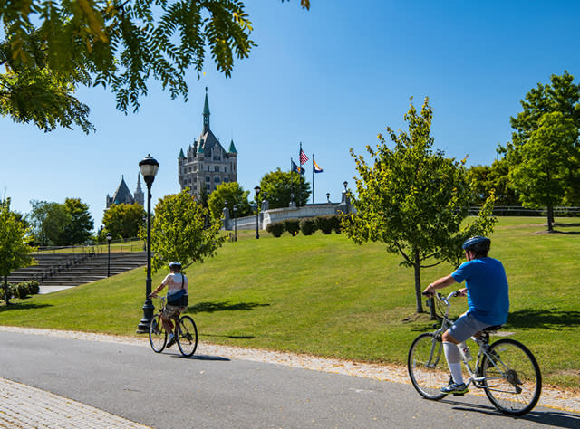 A photo of two people bicycling on the Empire Trail Corning Preserve