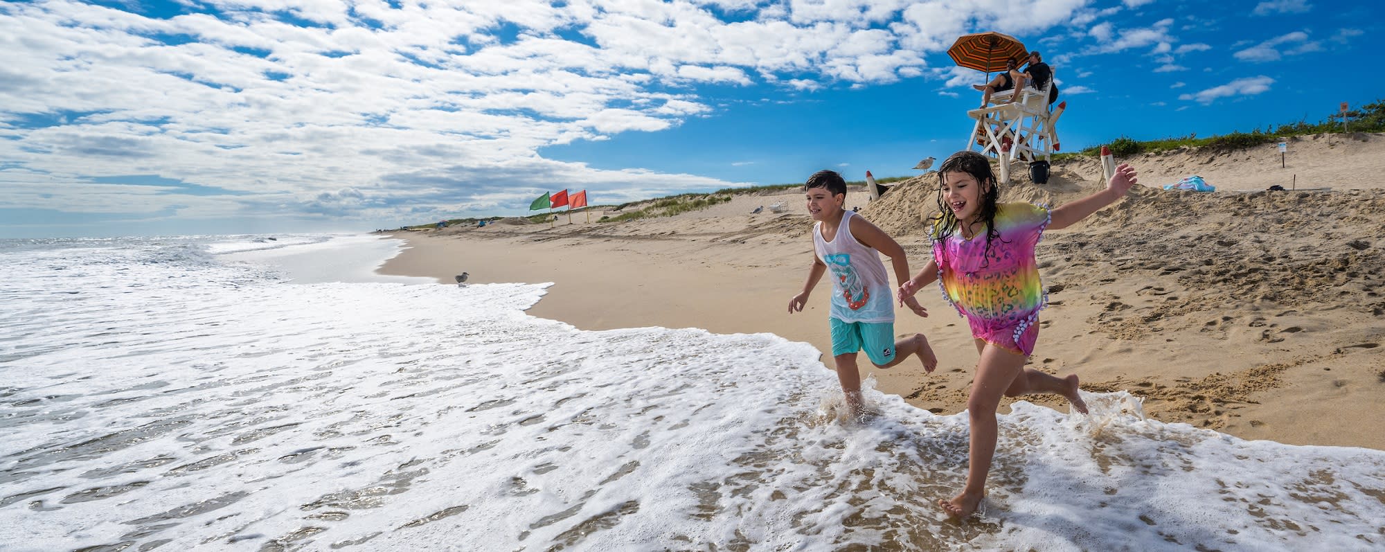 A boy and a girl run into the surf on the beach at Hither Hills State Park