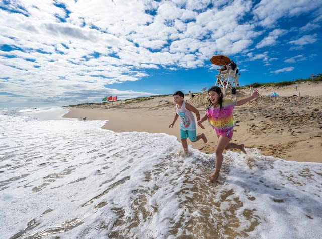 A boy and a girl run into the surf on the beach at Hither Hills State Park