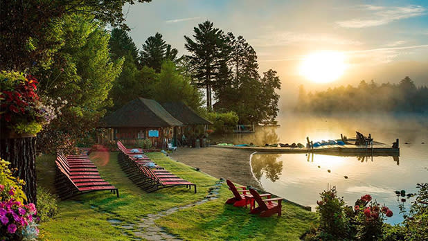 Red lounge chairs lined up along Mirror Lake at sunset at Mirror Lake Inn in Lake Placid