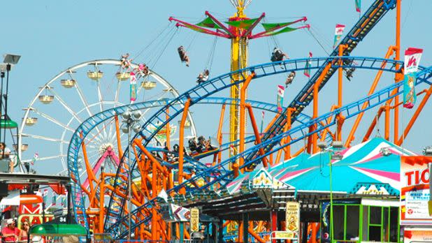 Rollercoaster rides and stalls at the New York State Fair on a clear sunny day