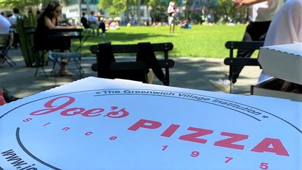 A box of pizza from Joe's Pizza sitting on a table in Bryant Park.