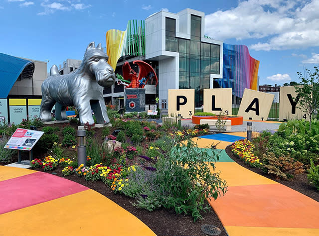 A giant Monopoly dog and Scrabble tile pieces spelling out the word "Play" stand in the winding Hasbro Game Park at the Strong National Museum of Play