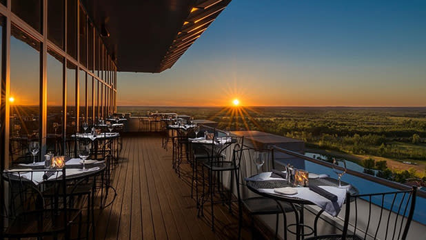 An outdoor dining area on a high floor with a view of sunset